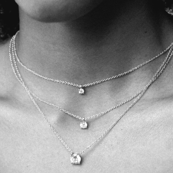 Superposition de chaînes en or avec pendentifs diamant, illustrant la différence entre chaîne, pendentif et collier porté autour du cou